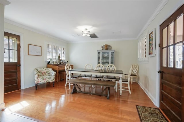 dining space with crown molding and wood-type flooring