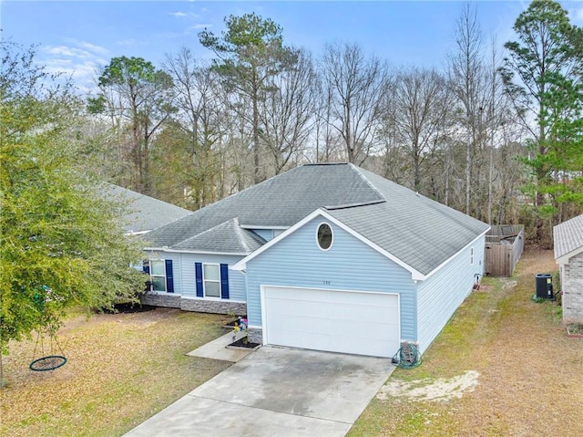 view of front of house featuring a garage, a front yard, and central AC unit