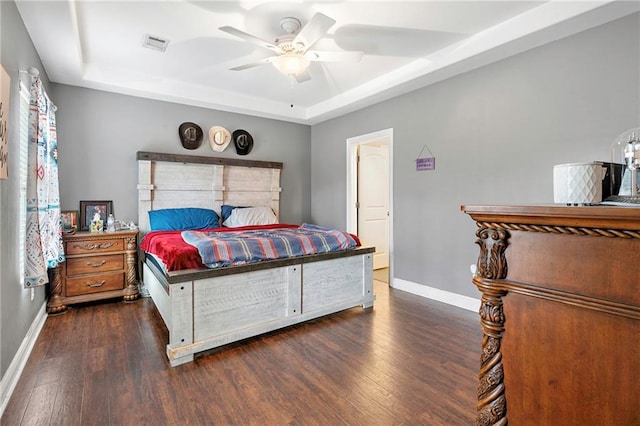 bedroom featuring dark wood-type flooring, a raised ceiling, and ceiling fan