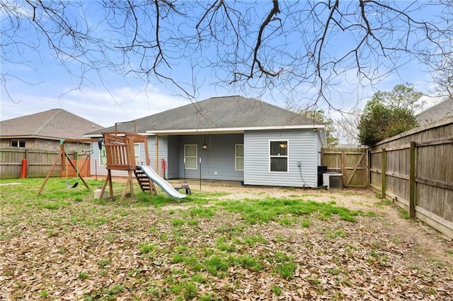 rear view of house with central AC unit and a playground