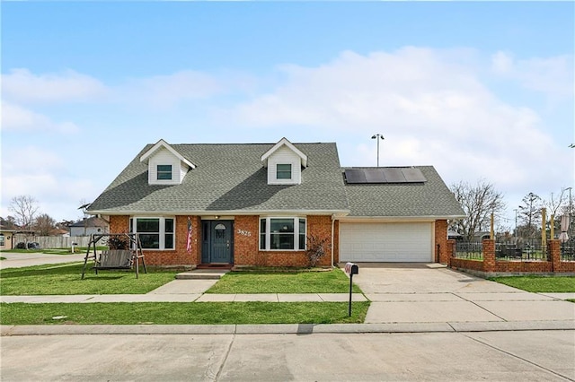 new england style home featuring a garage, a front yard, and solar panels