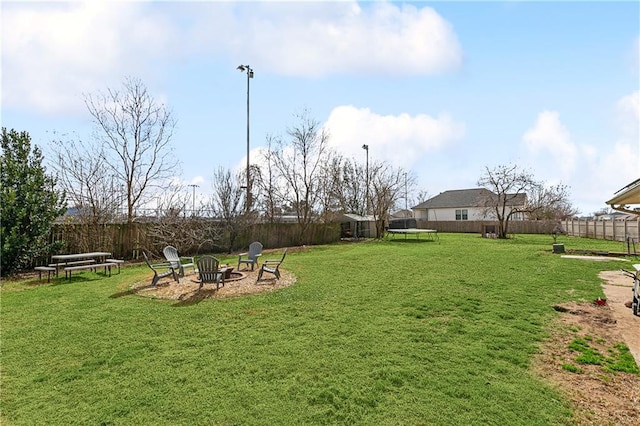 view of yard with a trampoline and an outdoor fire pit