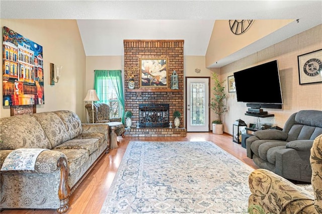 living room featuring a fireplace, light hardwood / wood-style floors, and vaulted ceiling