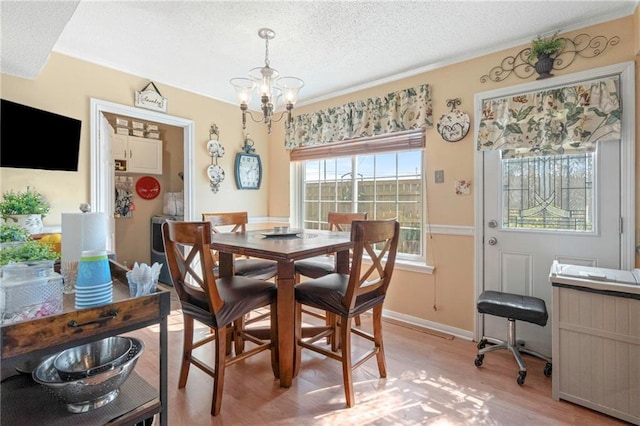 dining room featuring an inviting chandelier, a textured ceiling, and light wood-type flooring