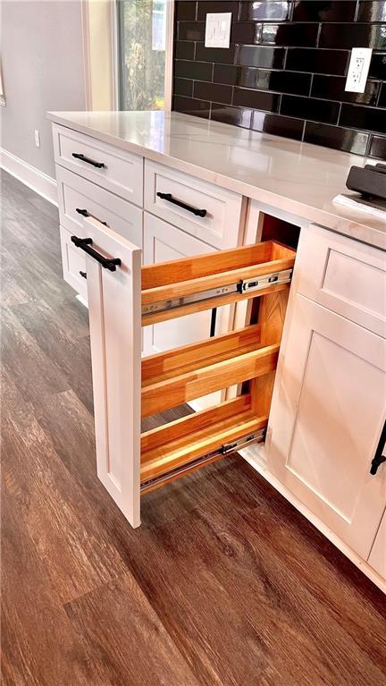 room details featuring tasteful backsplash, dark hardwood / wood-style floors, and white cabinets