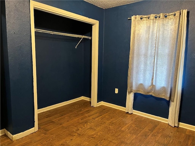 unfurnished bedroom with hardwood / wood-style flooring, a closet, and a textured ceiling
