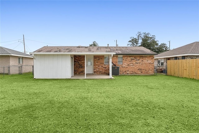 back of house featuring a fenced backyard, brick siding, a yard, and a patio area