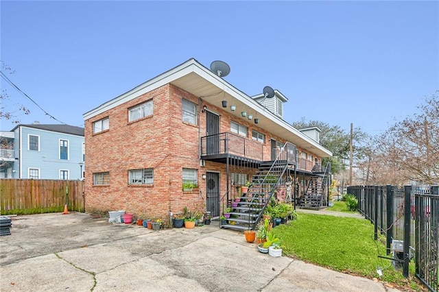 back of property featuring a patio, a balcony, and a lawn