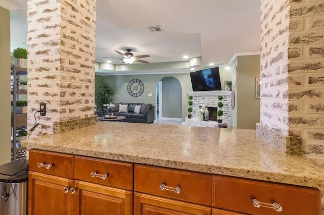 6900 Royal St, Arabi, LA 70032 - kitchen featuring arched walkways, a ceiling fan, light stone countertops, open floor plan, and ornamental molding