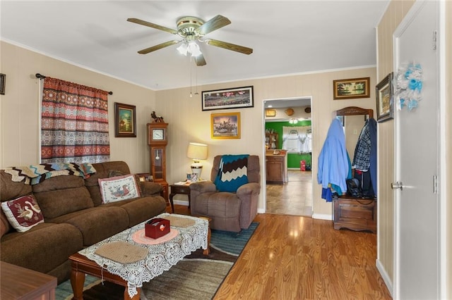 living room with wood-type flooring, ornamental molding, and ceiling fan