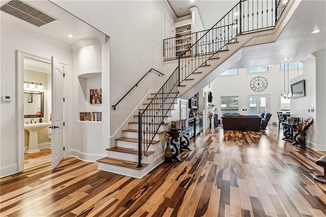 stairway with ornamental molding, a towering ceiling, hardwood / wood-style floors, and french doors