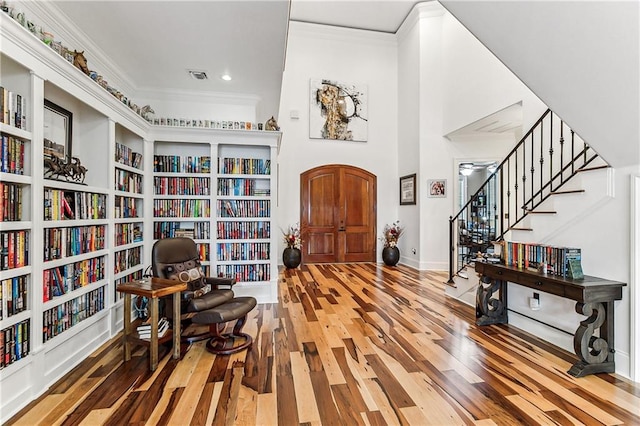 foyer with hardwood / wood-style floors, crown molding, and a towering ceiling