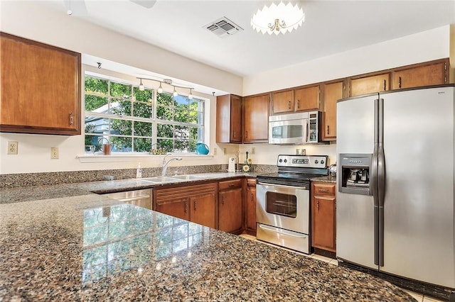 kitchen featuring dark stone countertops, sink, and appliances with stainless steel finishes