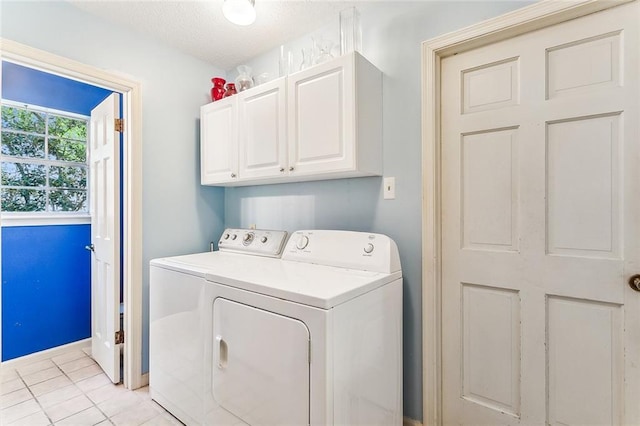 clothes washing area featuring cabinets, light tile patterned floors, and washer and clothes dryer