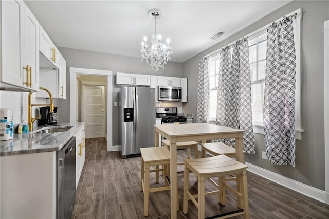 kitchen featuring sink, light stone counters, decorative light fixtures, stainless steel appliances, and white cabinets