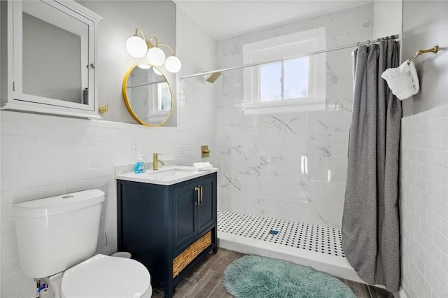 bathroom featuring tile walls, vanity, toilet, and walk in shower