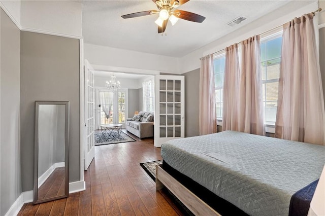 bedroom featuring ceiling fan with notable chandelier and dark hardwood / wood-style floors