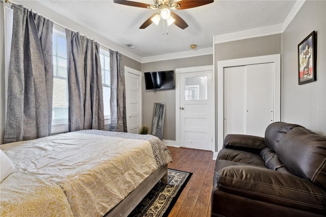 bedroom featuring ceiling fan, dark wood-type flooring, ornamental molding, and a textured ceiling