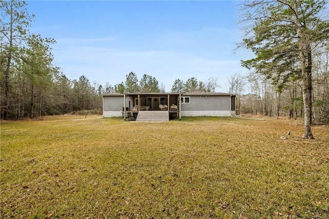 rear view of house featuring a yard and a sunroom