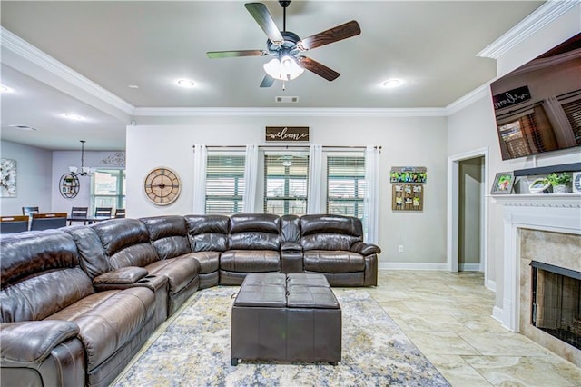 living room featuring a tile fireplace, ornamental molding, and ceiling fan with notable chandelier