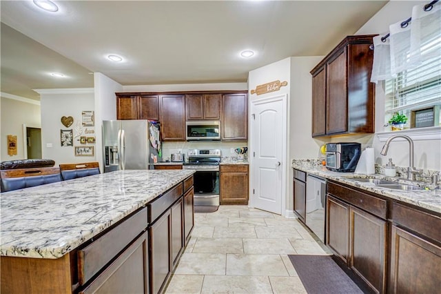 kitchen with appliances with stainless steel finishes, sink, decorative backsplash, a center island, and light stone counters