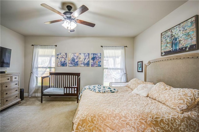 bedroom featuring ceiling fan, multiple windows, and light carpet