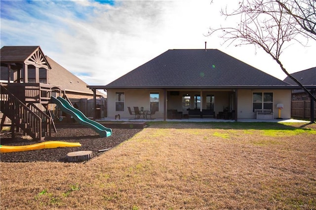 rear view of property featuring a yard, a playground, and a patio area