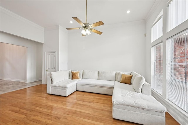 living room with crown molding, light hardwood / wood-style flooring, ceiling fan, and a towering ceiling