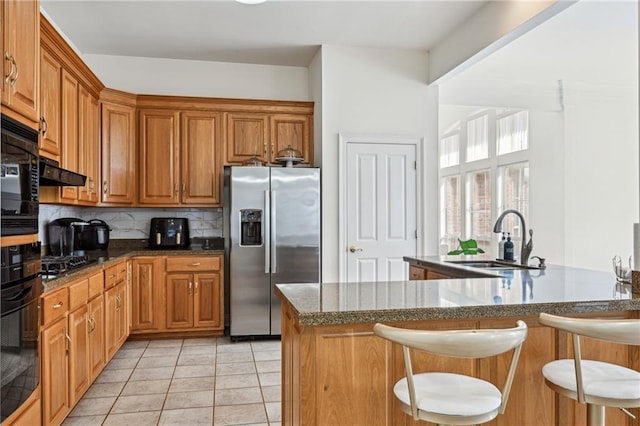 kitchen with a breakfast bar, tasteful backsplash, sink, kitchen peninsula, and stainless steel refrigerator with ice dispenser