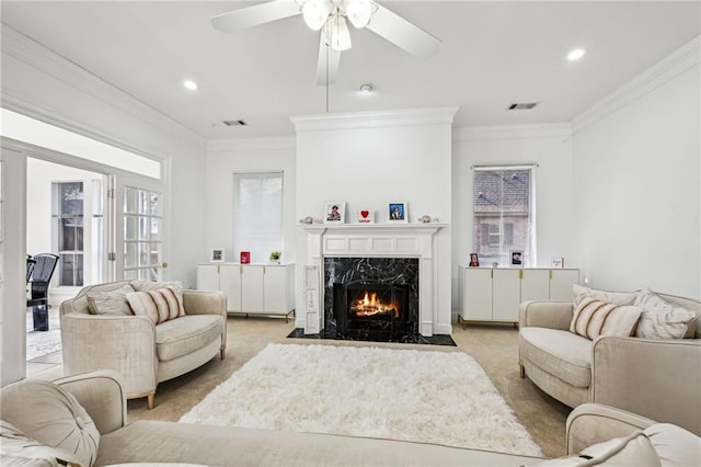 living room with crown molding, light colored carpet, a high end fireplace, and ceiling fan