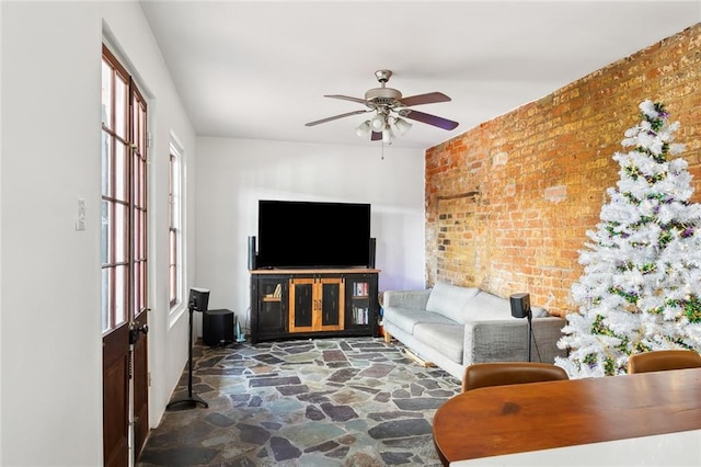 living room with ceiling fan and brick wall