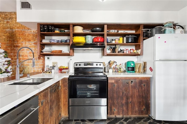 kitchen with sink, appliances with stainless steel finishes, dark brown cabinets, light stone countertops, and brick wall