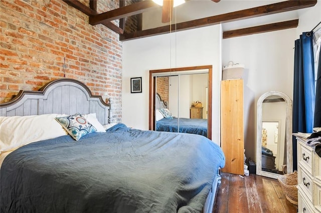 bedroom featuring dark hardwood / wood-style flooring, a closet, brick wall, beam ceiling, and a high ceiling