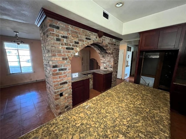 kitchen featuring dark tile patterned floors, dark brown cabinets, and stone counters