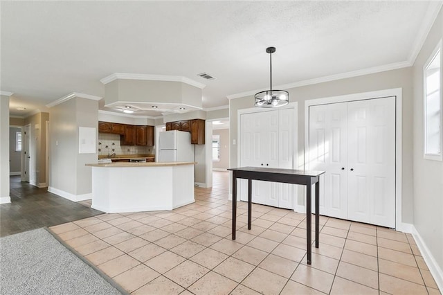 kitchen featuring tasteful backsplash, light tile patterned floors, ornamental molding, and white fridge