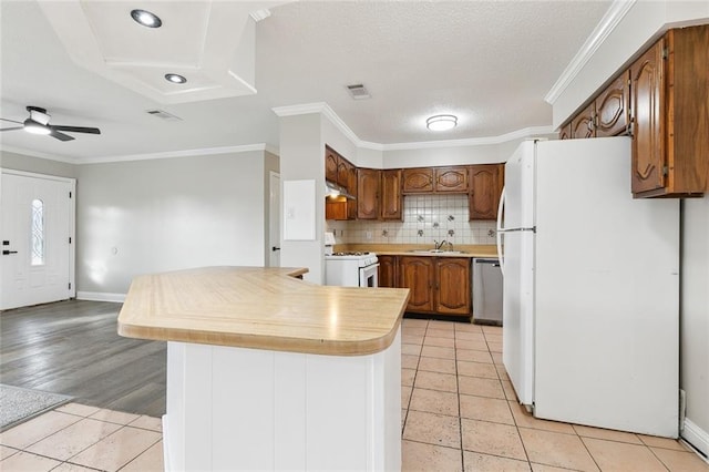 kitchen featuring sink, light tile patterned floors, ornamental molding, white appliances, and backsplash