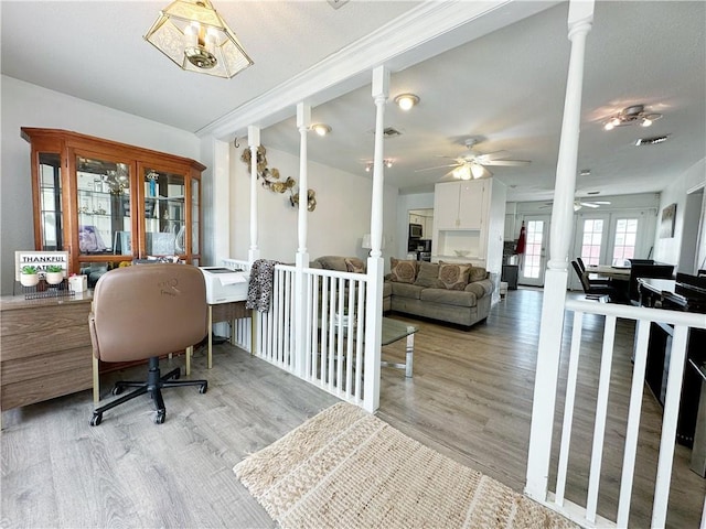 home office with decorative columns and light wood-type flooring