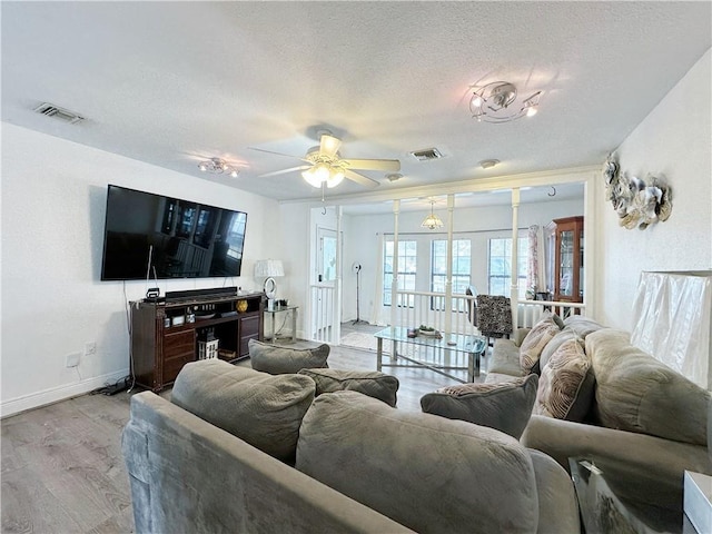 living room with ceiling fan, light hardwood / wood-style floors, and a textured ceiling