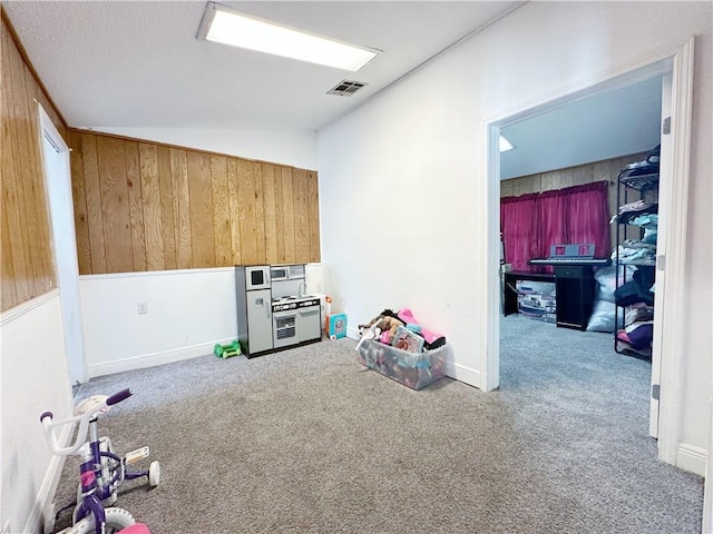 interior space featuring vaulted ceiling, carpet floors, and wood walls