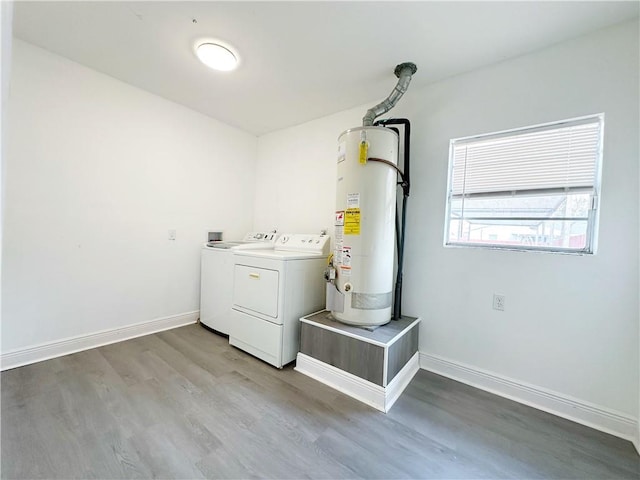 laundry area with wood-type flooring, washing machine and dryer, and water heater