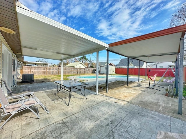 view of patio / terrace featuring a fenced in pool, central air condition unit, and a storage shed