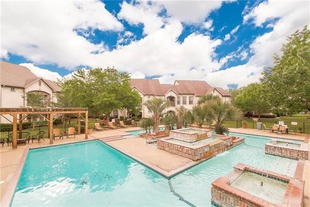 view of swimming pool with a hot tub, pool water feature, a pergola, and a patio area