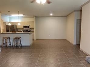 kitchen with a breakfast bar, appliances with stainless steel finishes, ornamental molding, kitchen peninsula, and ceiling fan