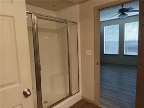 bathroom with walk in shower and ceiling fan