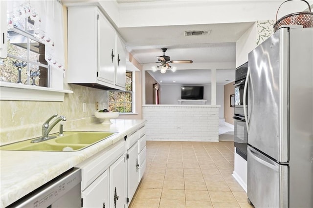 kitchen featuring sink, white cabinetry, light tile patterned floors, stainless steel fridge, and dishwasher