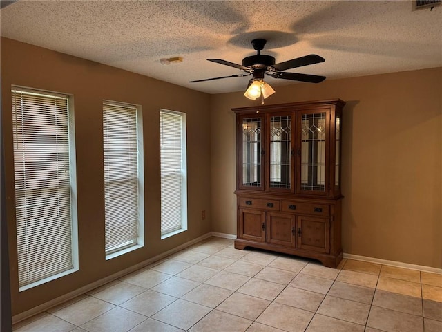 205 Hollow Rock Ct, Slidell, LA 70461 - unfurnished dining area featuring ceiling fan, light tile patterned floors, baseboards, and a textured ceiling