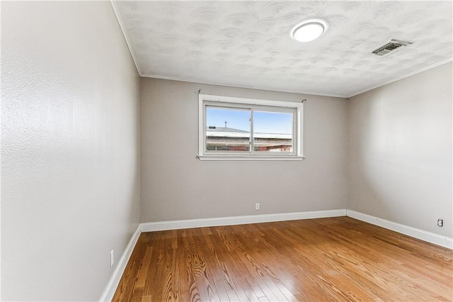 spare room featuring hardwood / wood-style floors and crown molding