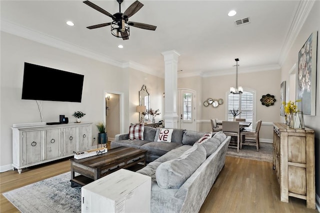 living room with decorative columns, ornamental molding, ceiling fan, and light wood-type flooring