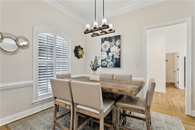 dining space featuring an inviting chandelier, ornamental molding, and light hardwood / wood-style flooring