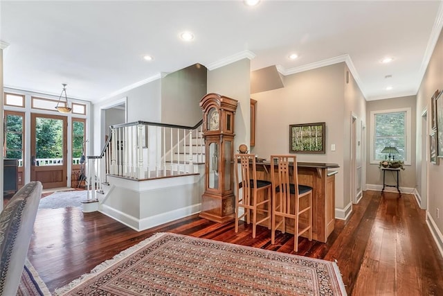 staircase with wood-type flooring, a healthy amount of sunlight, bar area, and ornamental molding